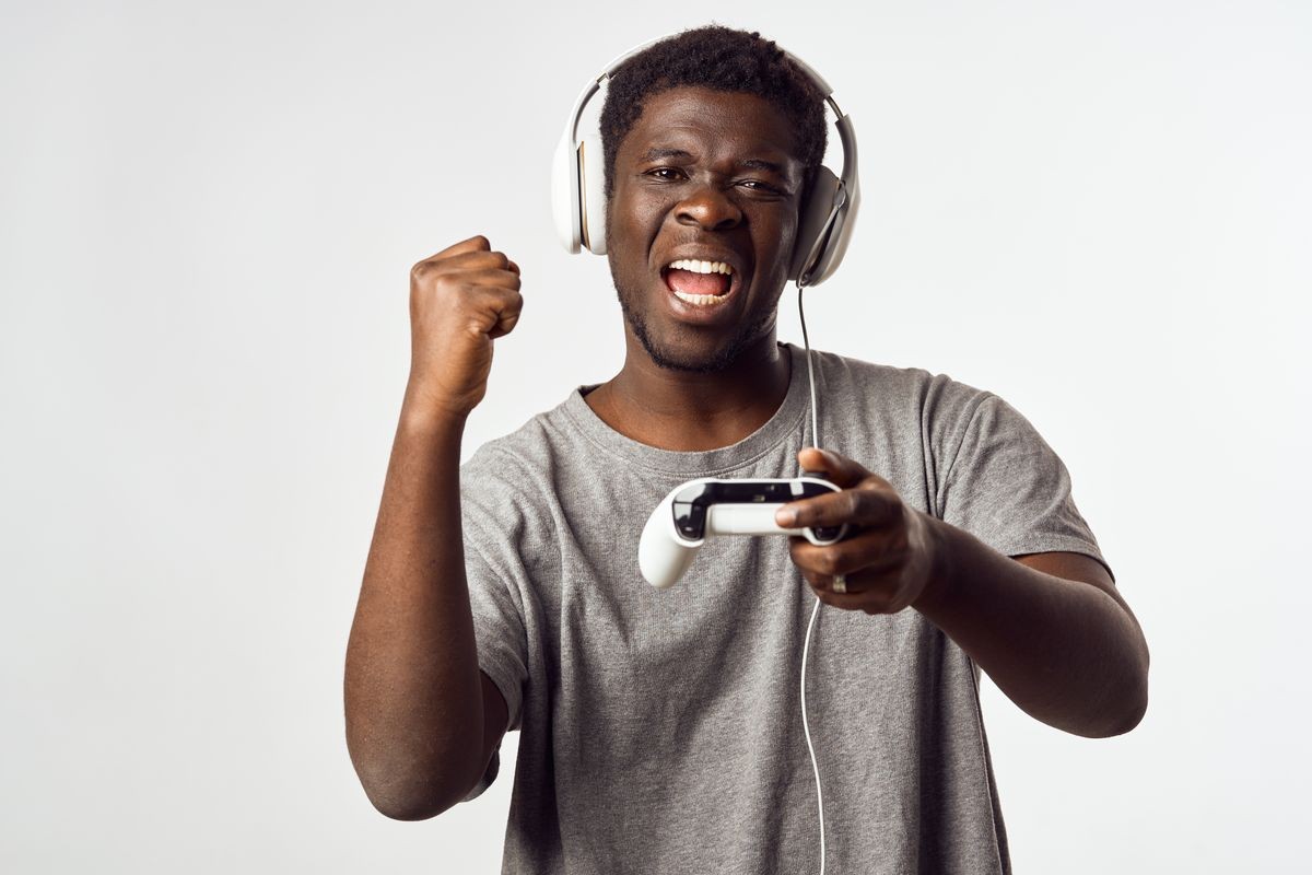 Cheerful male of African appearance in headphones with a controller in his hands from the gaming console
